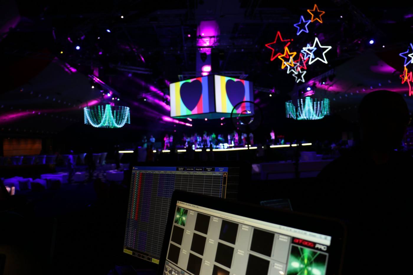 Lighting console in the foreground of a lit concert stage