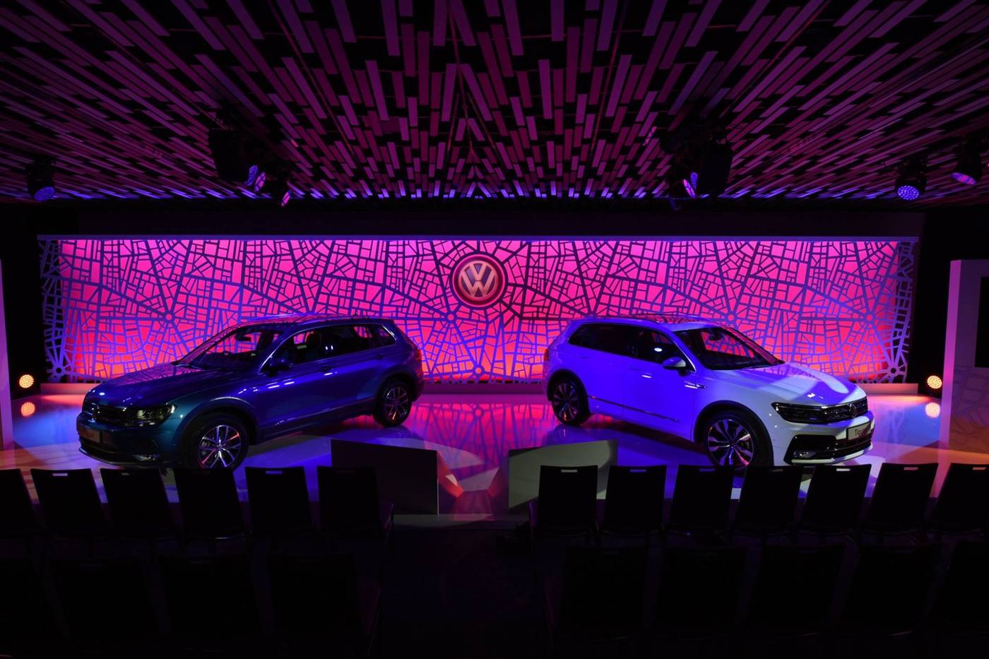 Two VW Tiguans in front of a magenta patterned backdrop